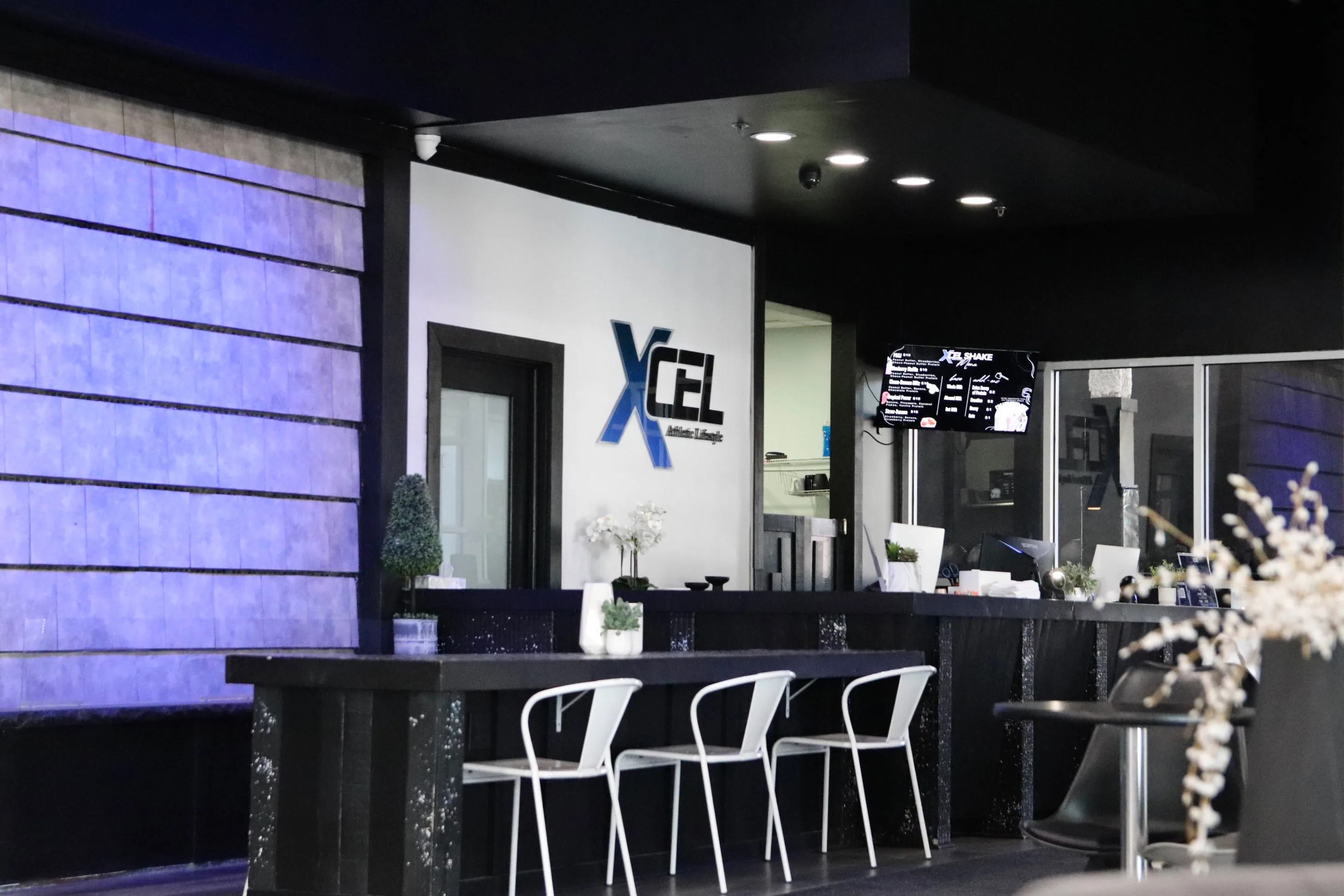 Front desk and member lounge with the XCEL logo at XCEL Athletic Lifestyle, a rooftop gym in Hoboken, NJ