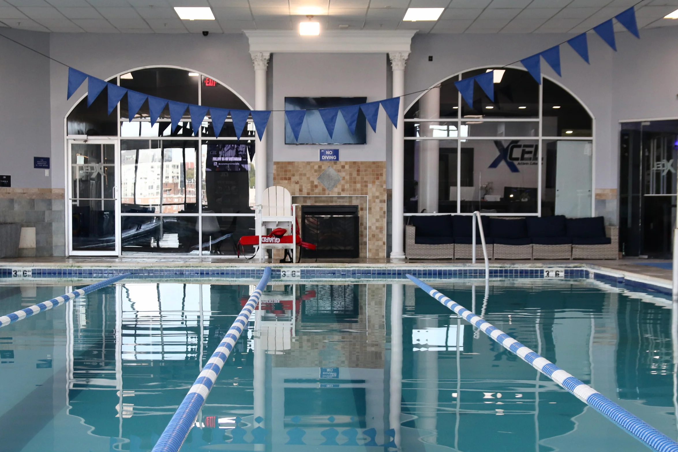 Heated indoor lap pool with lane lines and swim flags at XCEL Athletic Lifestyle, a rooftop gym in Hoboken, NJ