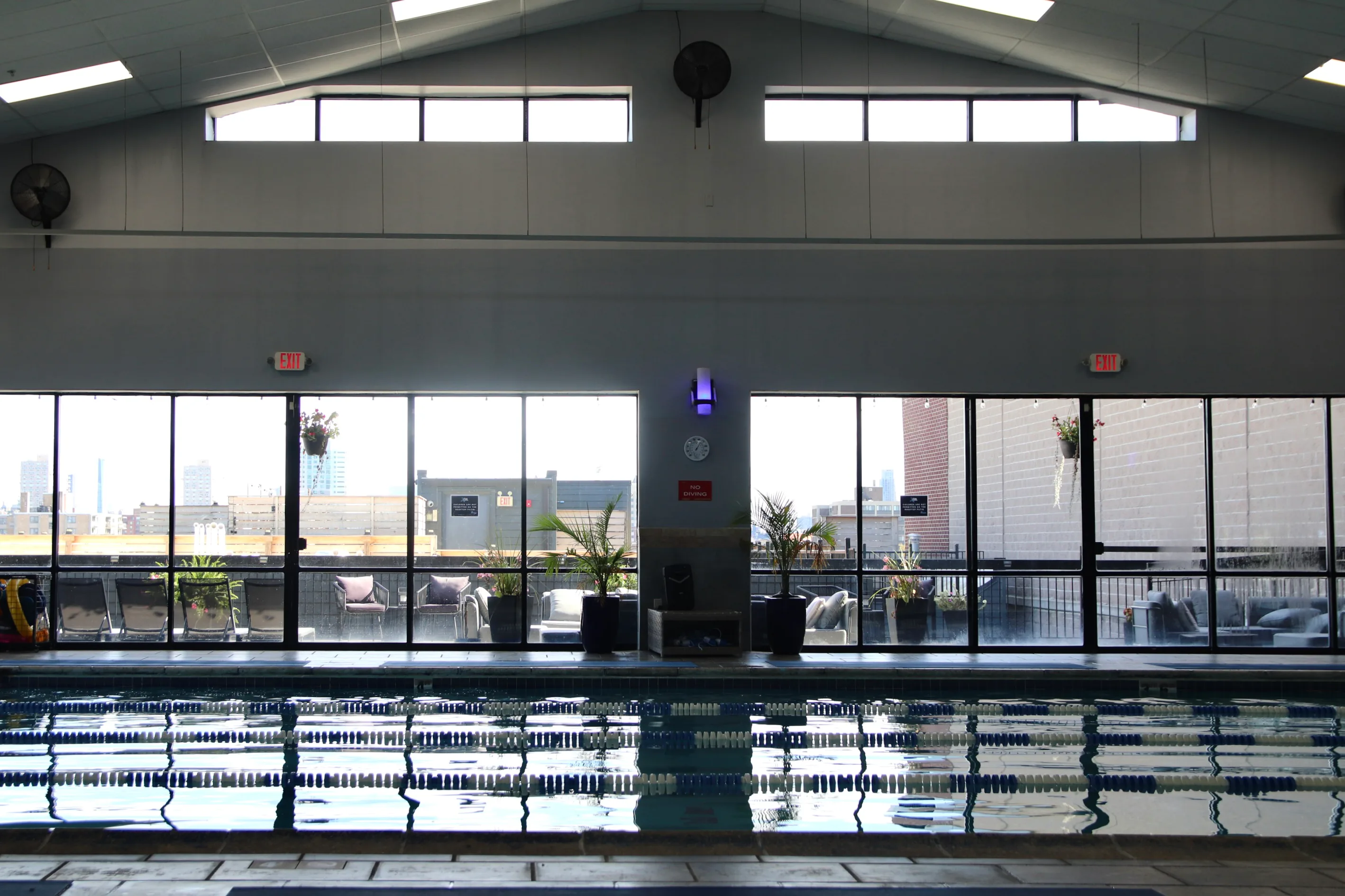Heated indoor lap pool with floor-to-ceiling windows at XCEL Athletic Lifestyle, a rooftop gym in Hoboken, NJ