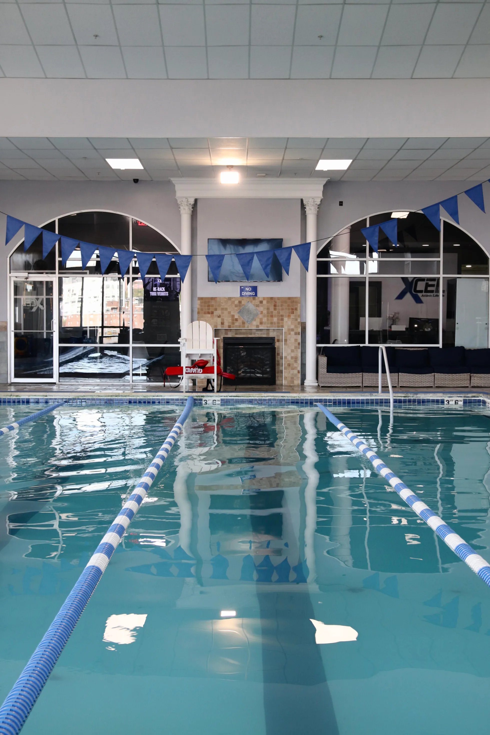 Heated indoor lap pool with lane lines and swim flags at XCEL Athletic Lifestyle, a rooftop gym in Hoboken, NJ